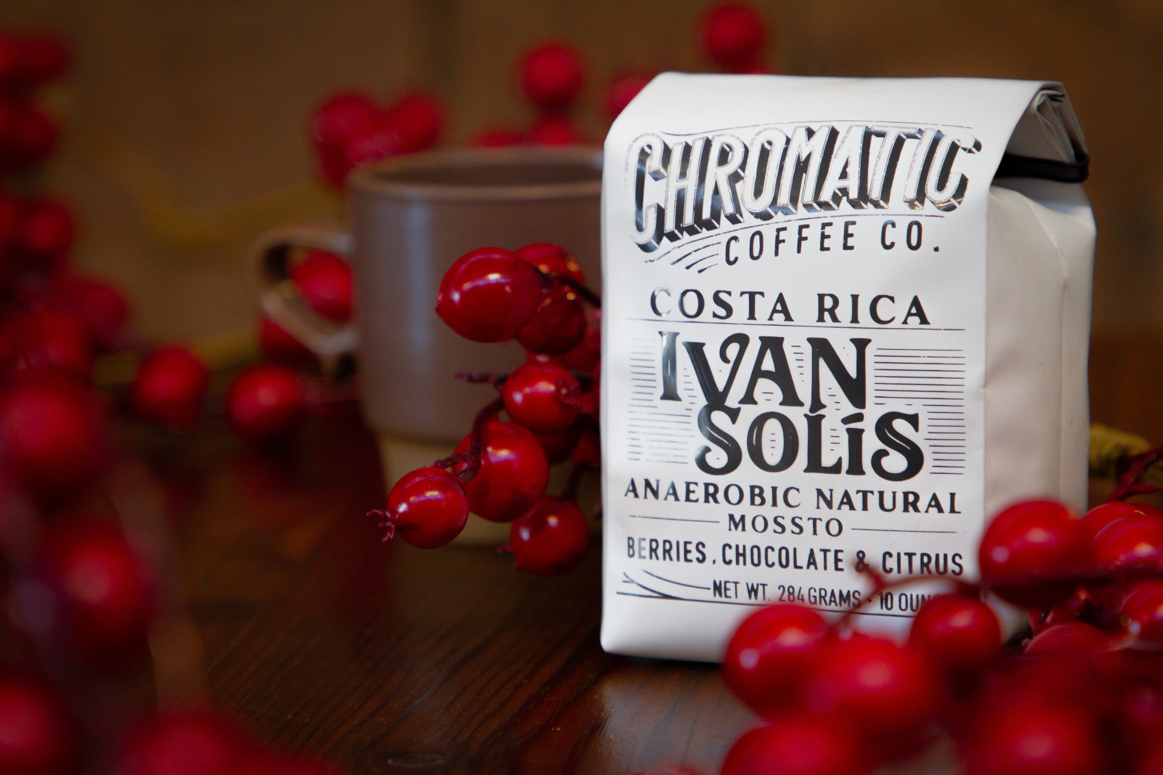 Coffee bag from Chromatic Coffee Co. with red berries around on a wooden surface